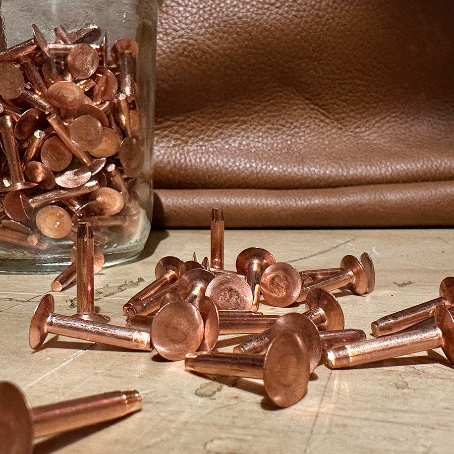 A jar of copper rivets on a wooden table
