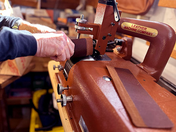 Person slides a piece of leather through the skiver machine